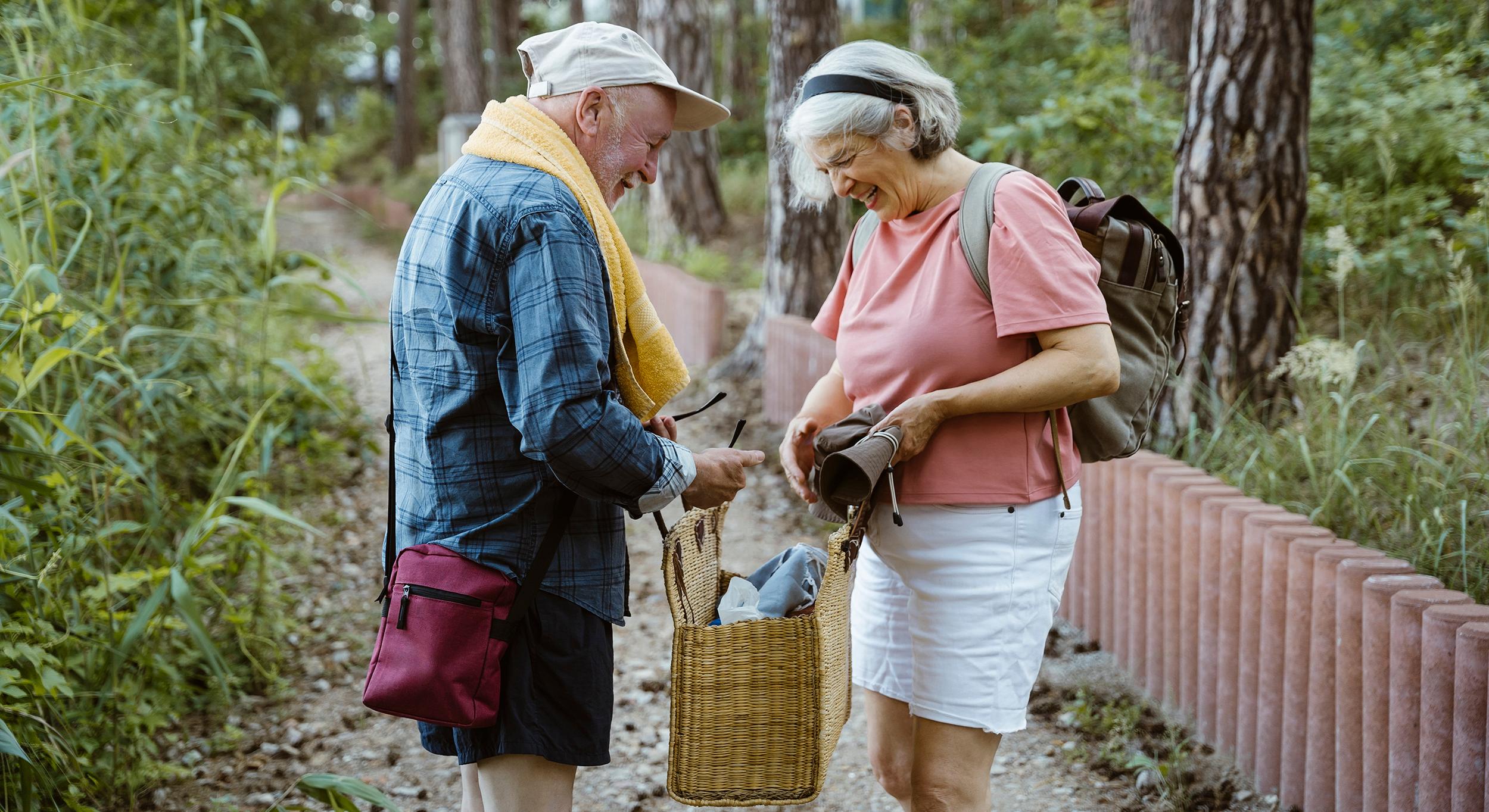 En äldre man och en äldre kvinna stor mot varandra hållandes i en picknicväska.